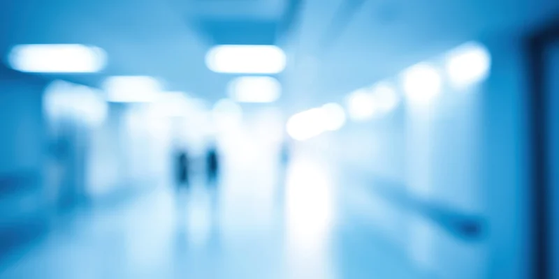 Blurred view of a long blue-toned indoor corridor with diffused fluorescent lighting and receding perspective