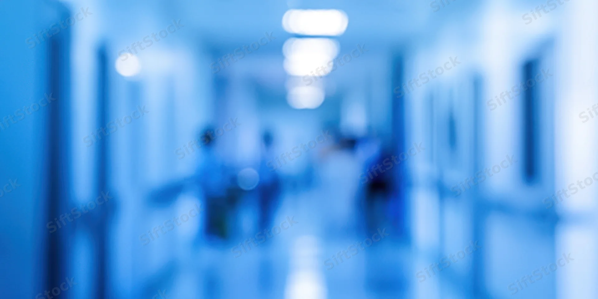 Blurred blue-toned indoor corridor with diffused lighting and indistinct figures in motion