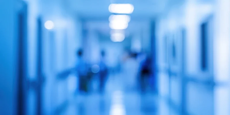 Blurred blue-toned indoor corridor with diffused lighting and indistinct figures in motion