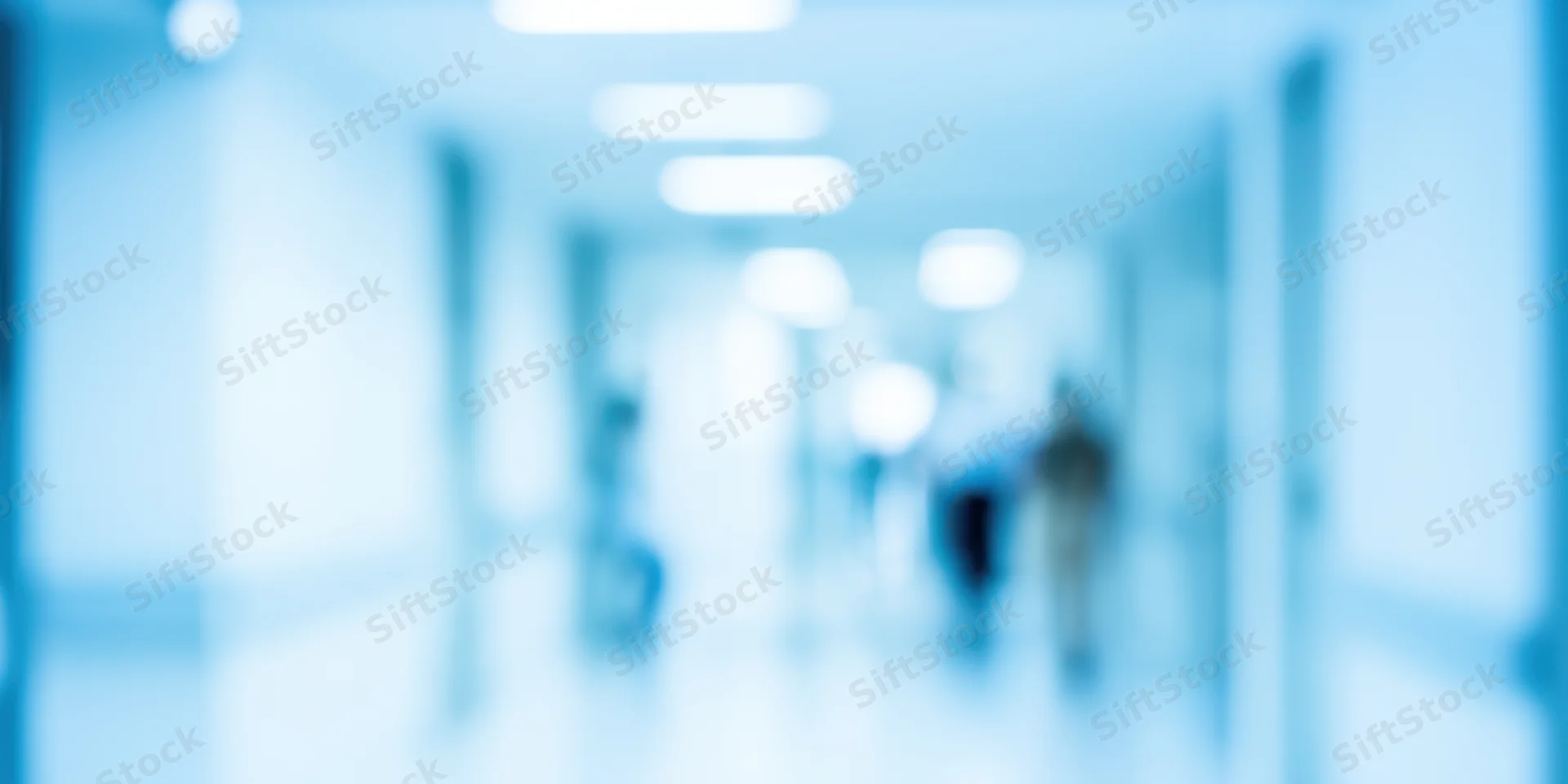 Blurred view of a cool blue-toned office hallway with diffused ceiling lights and indistinct figures moving in the distance