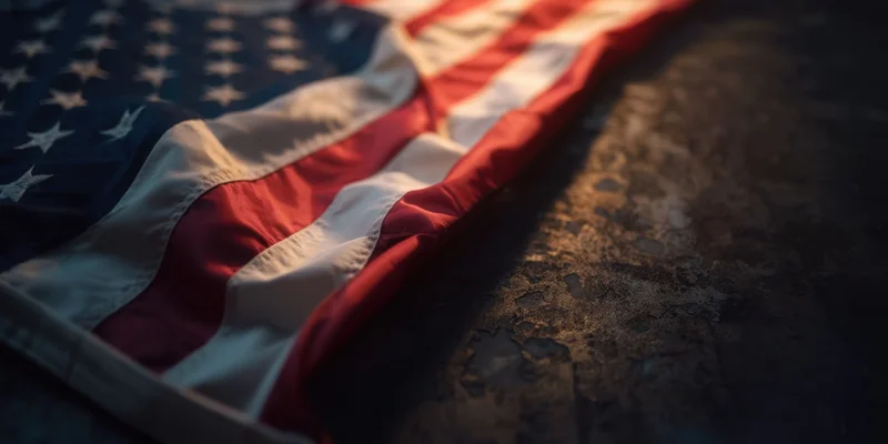 American flag folded along left edge resting on dark textured surface