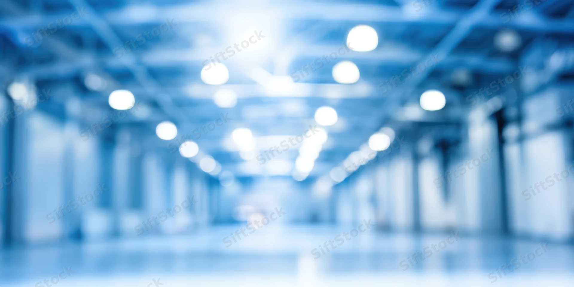 Blurred industrial interior with bright overhead lights in a long corridor