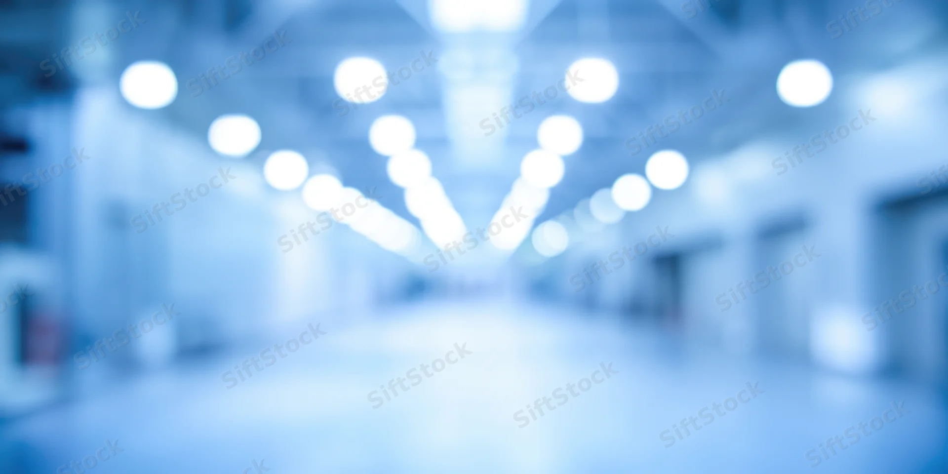 Blurred industrial hallway with bright overhead lights receding into distance