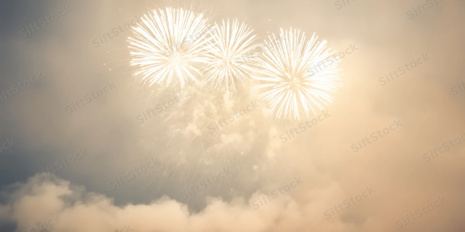 White fireworks bursting in a hazy night sky above clouds