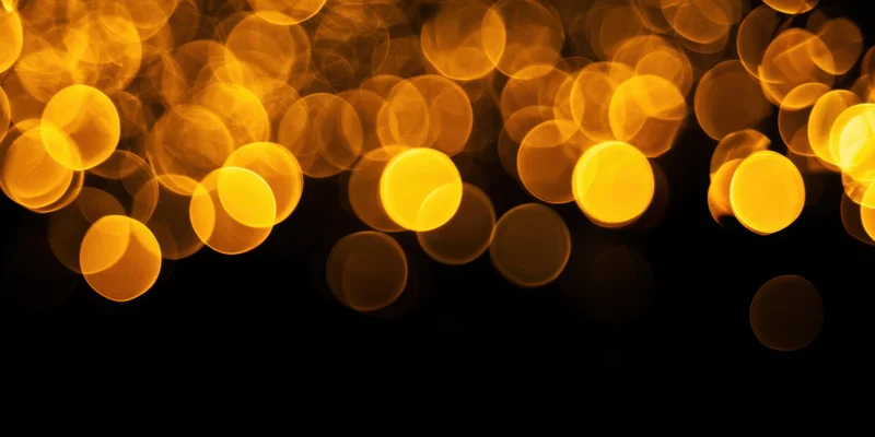 Warm golden bokeh orbs scattered across a black background with copyspace below