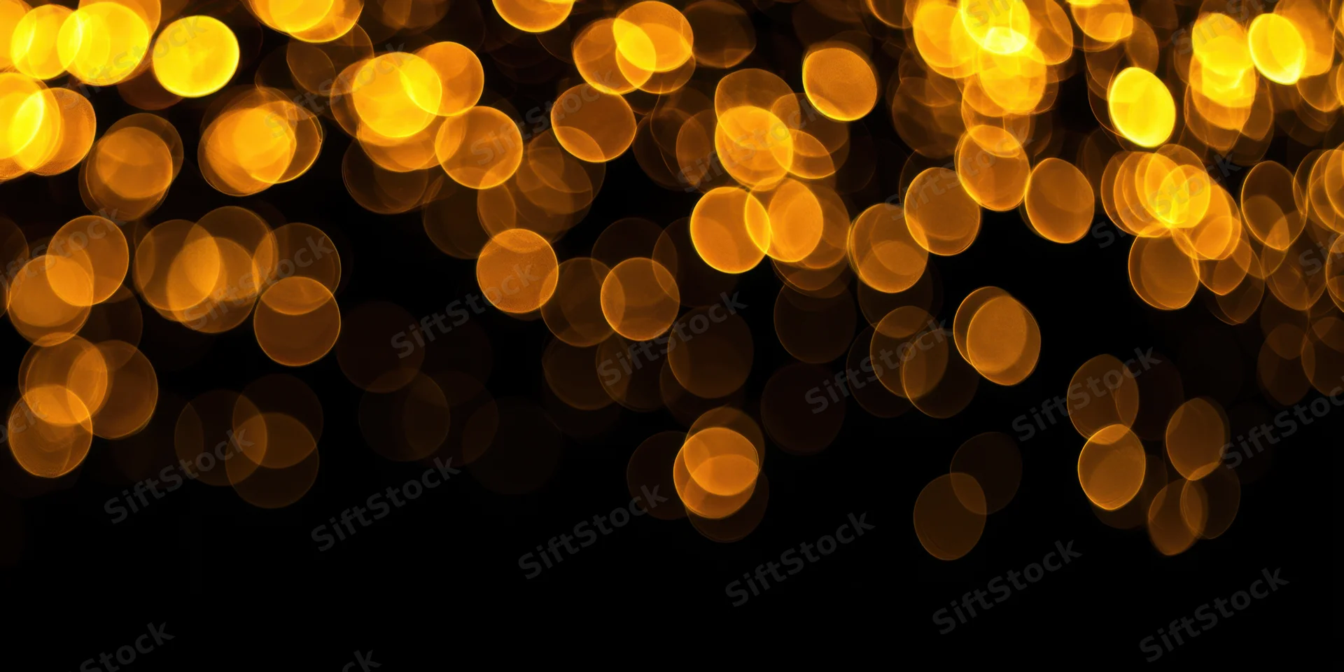 Warm golden bokeh lights scattered across a black background with copyspace