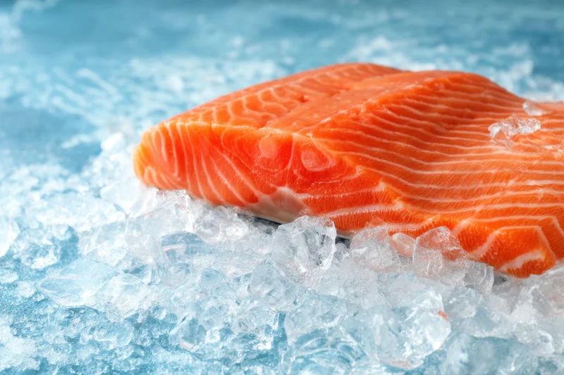 Fresh salmon fillet resting on crushed ice with vibrant orange flesh and white fat striations