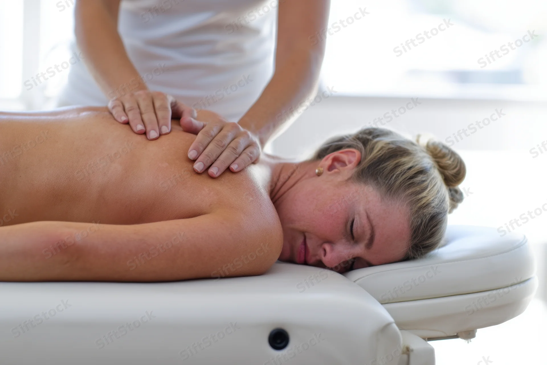Woman receiving back massage on massage chair with eyes closed