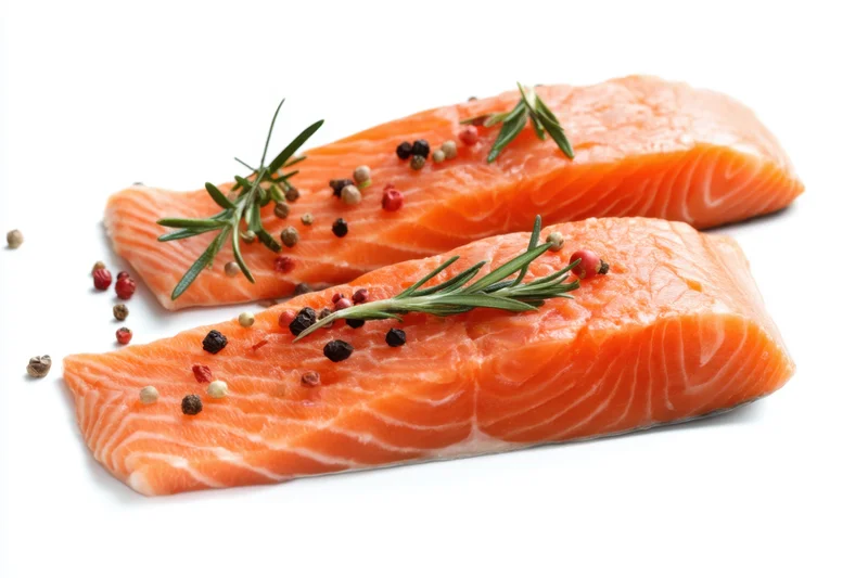 Two raw salmon fillets garnished with rosemary and peppercorns on a white background