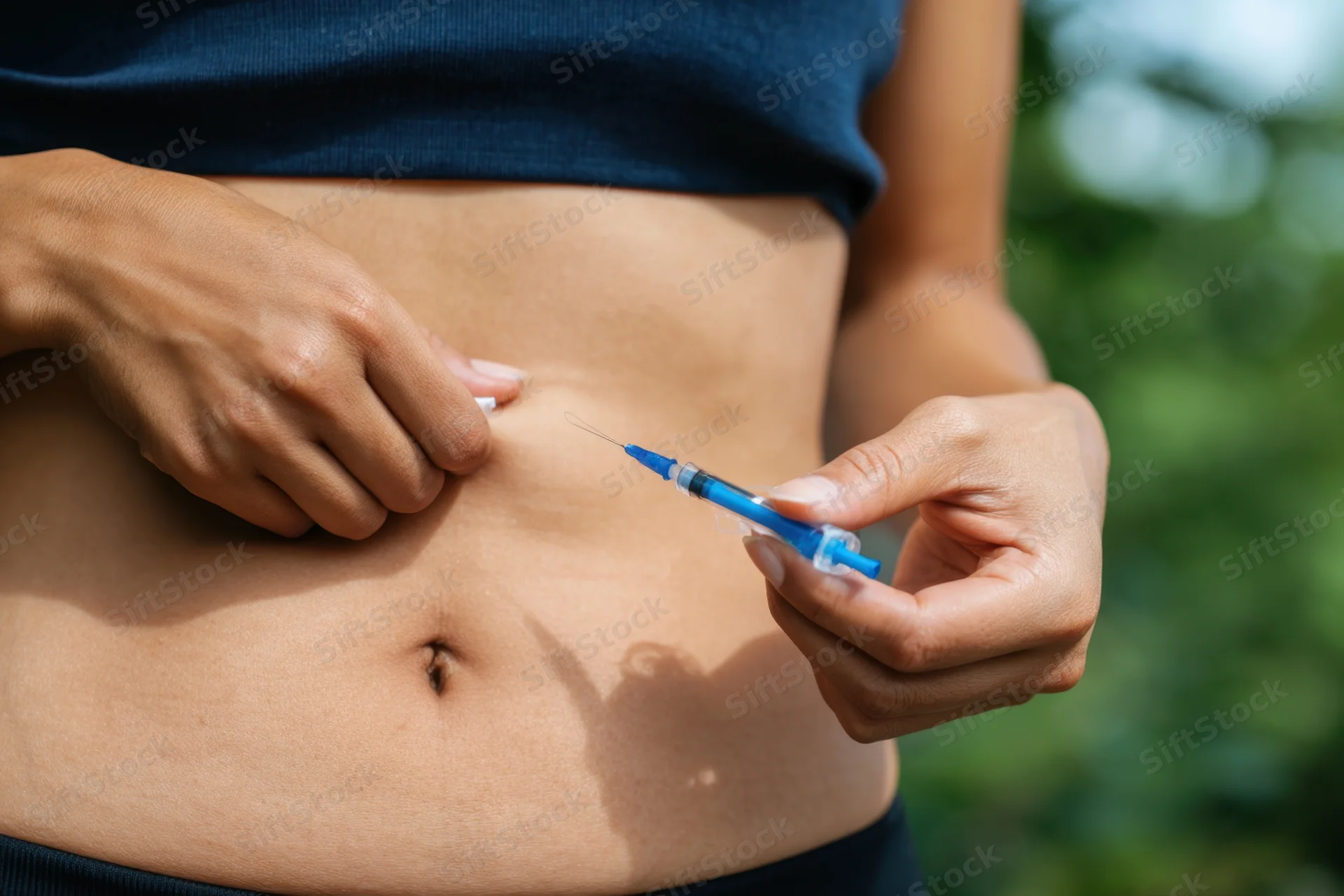 Woman injecting insulin into her abdomen outdoors during daytime