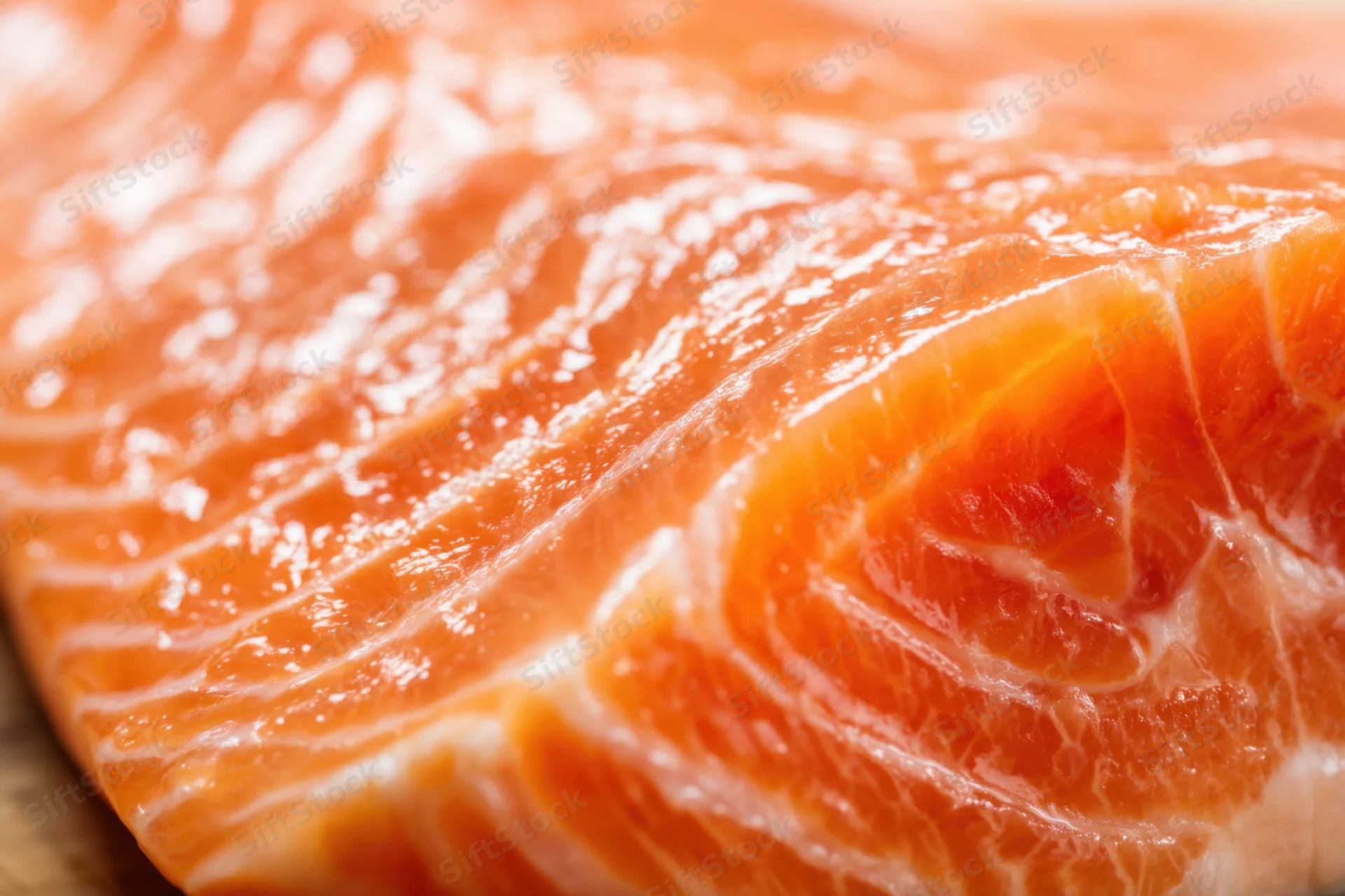 Close-up of a raw salmon fillet showing orange flesh and white marbling