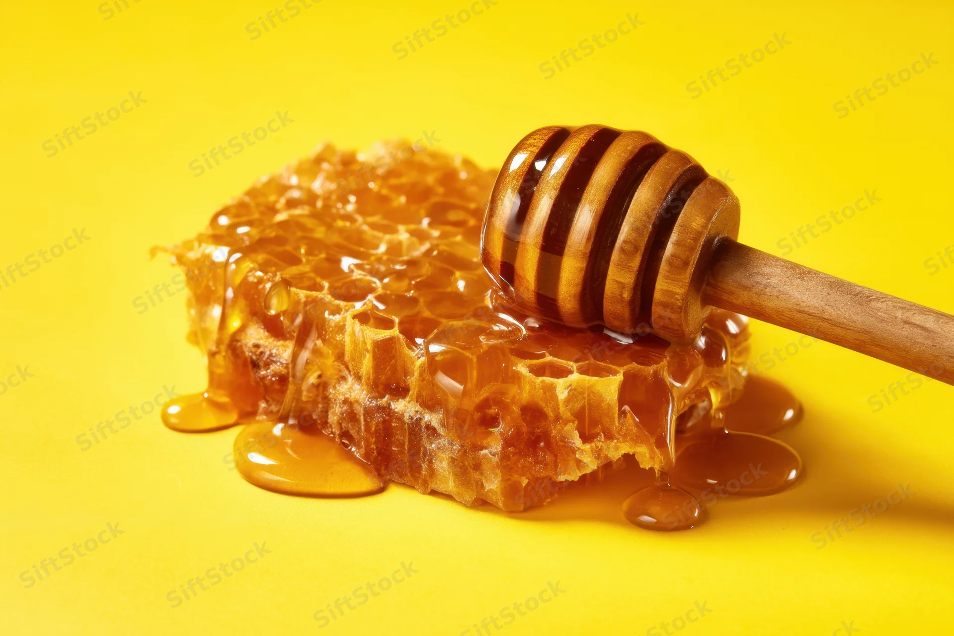 Honeycomb with dripping honey and wooden dipper on yellow background