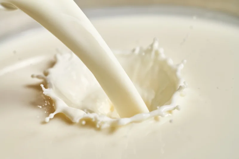 Milk being poured into a container creating a splash and ripple effect