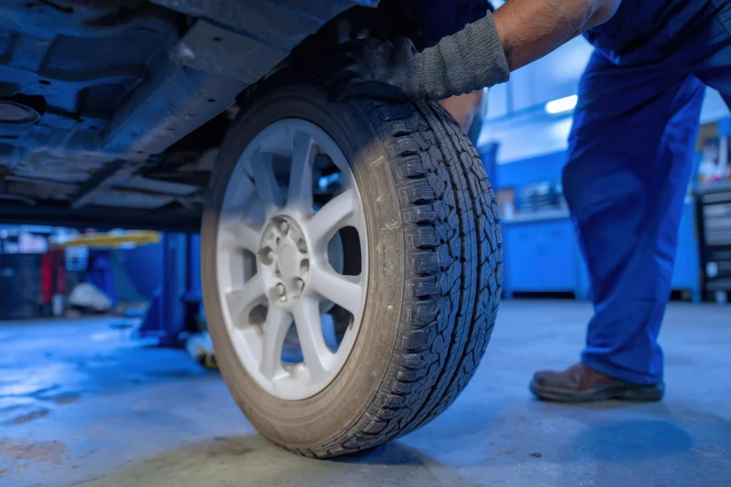 Mechanic replacing car tire in workshop garage