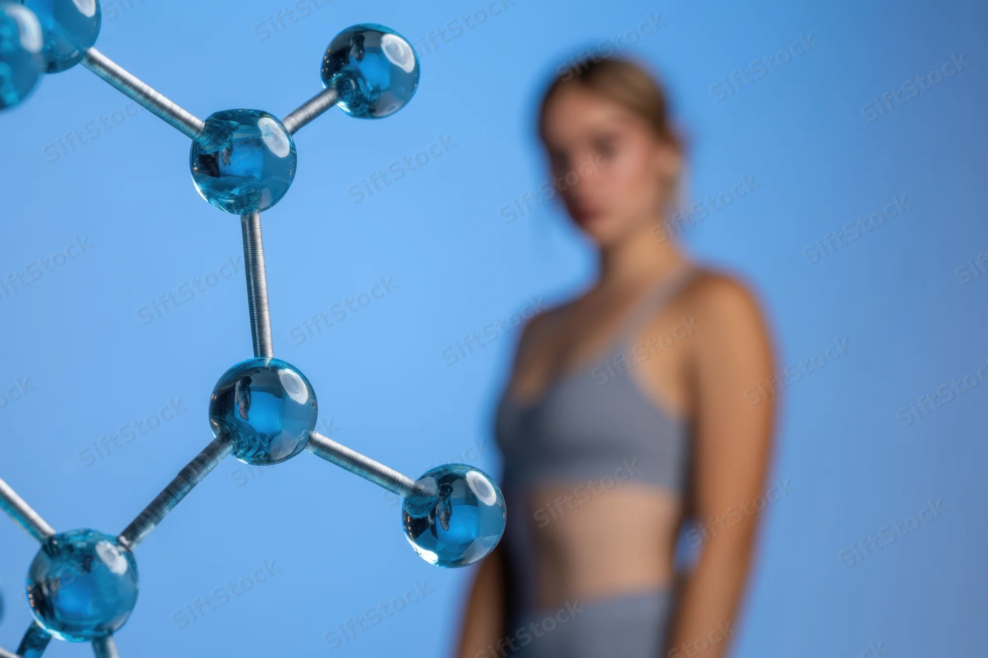 Closeup of a blue molecular model with a blurred woman in the background