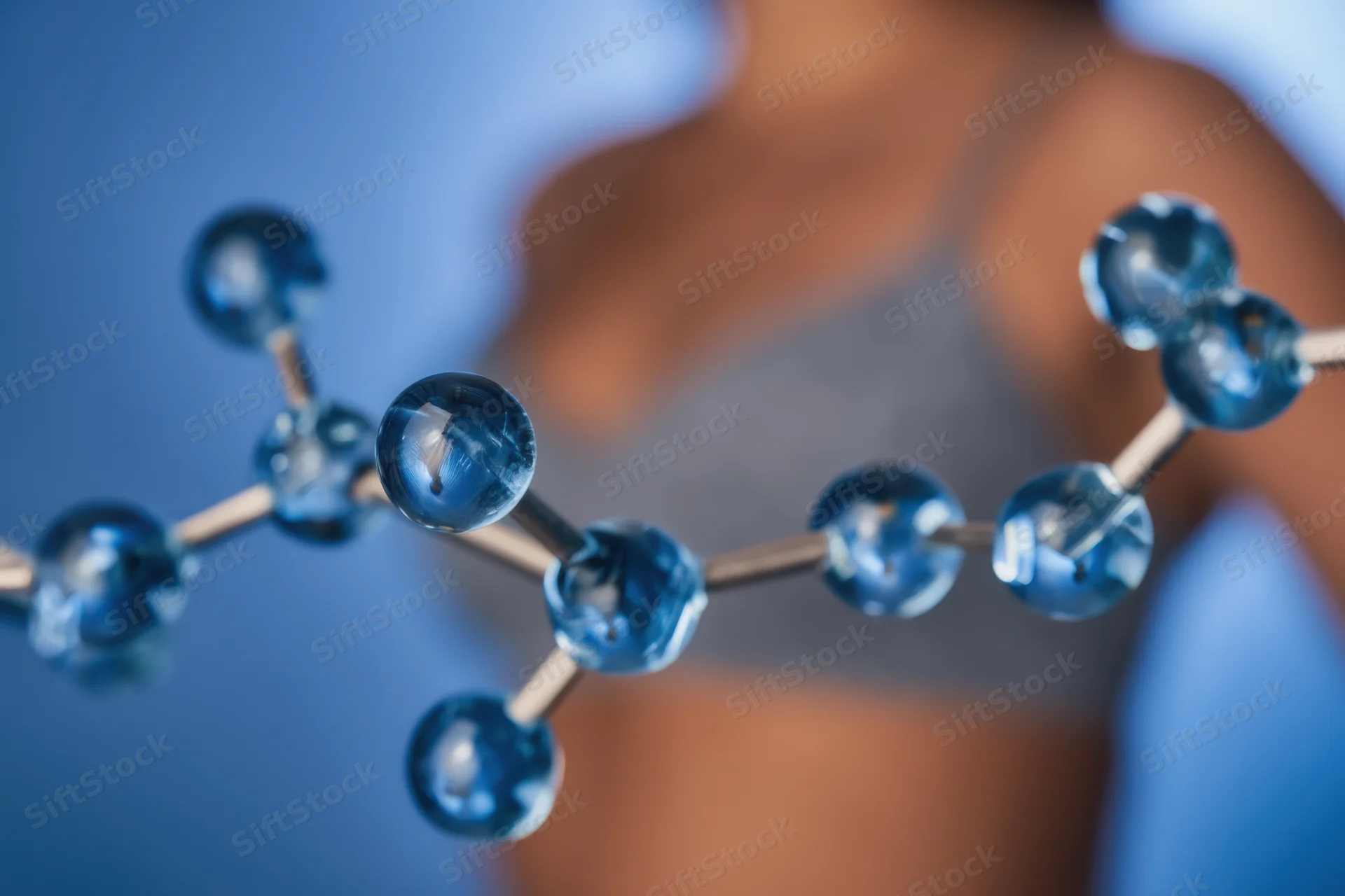 Close-up of a blue glass molecular model with interconnected spheres and rods, held in a laboratory setting