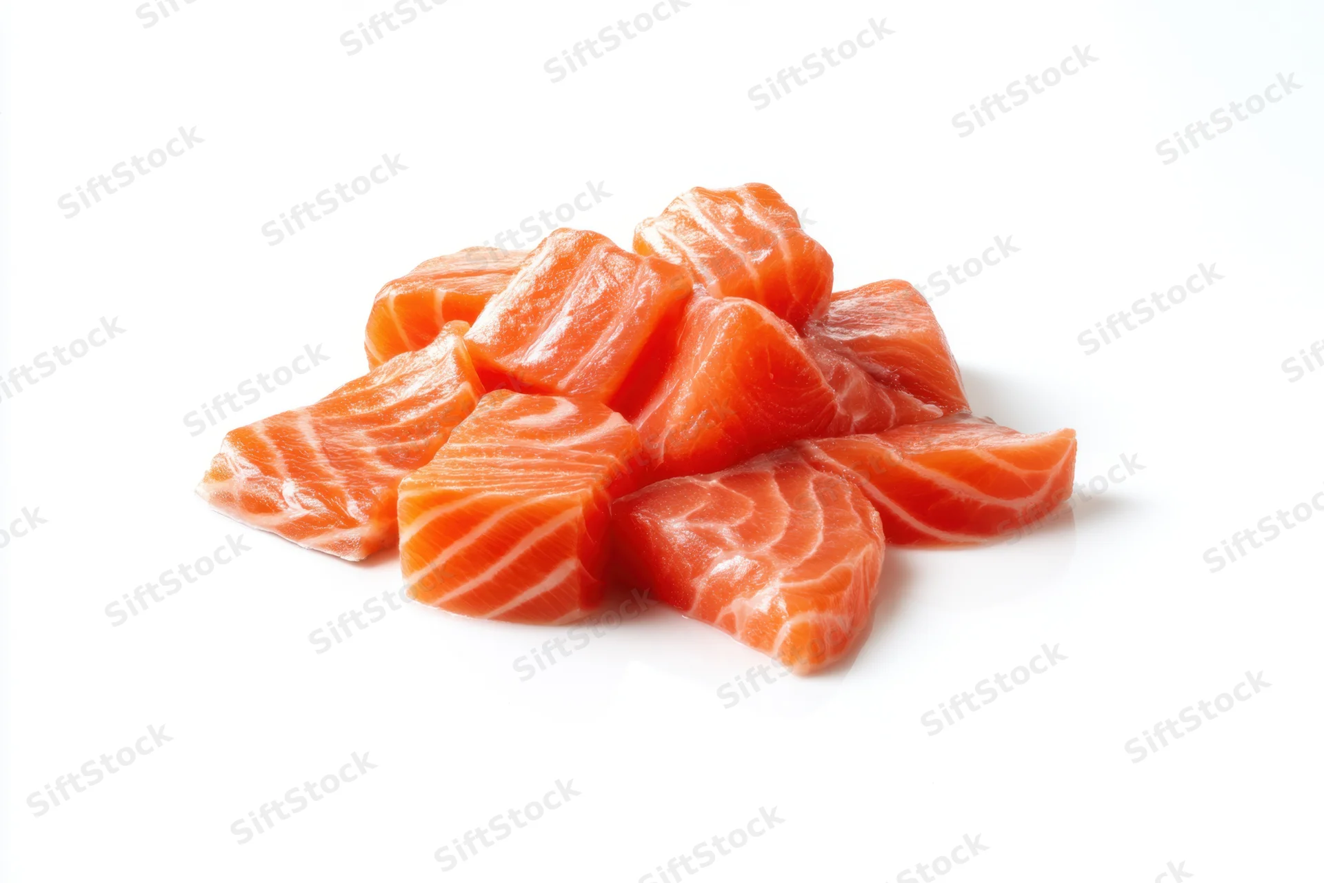 Raw salmon chunks arranged in a pile on a white background