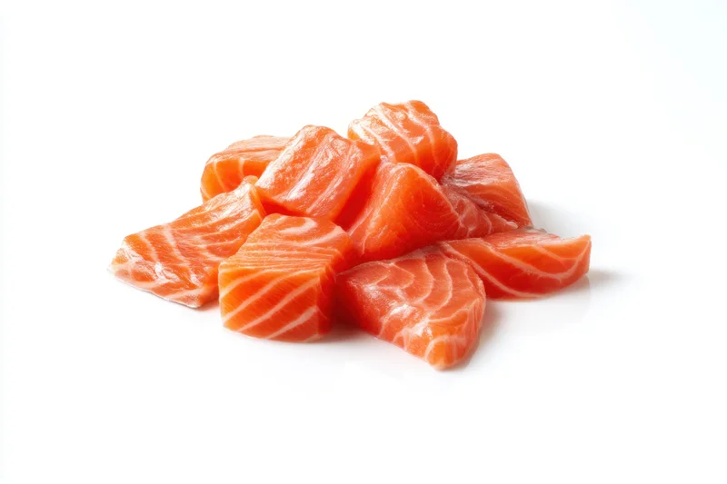 Raw salmon chunks arranged in a pile on a white background