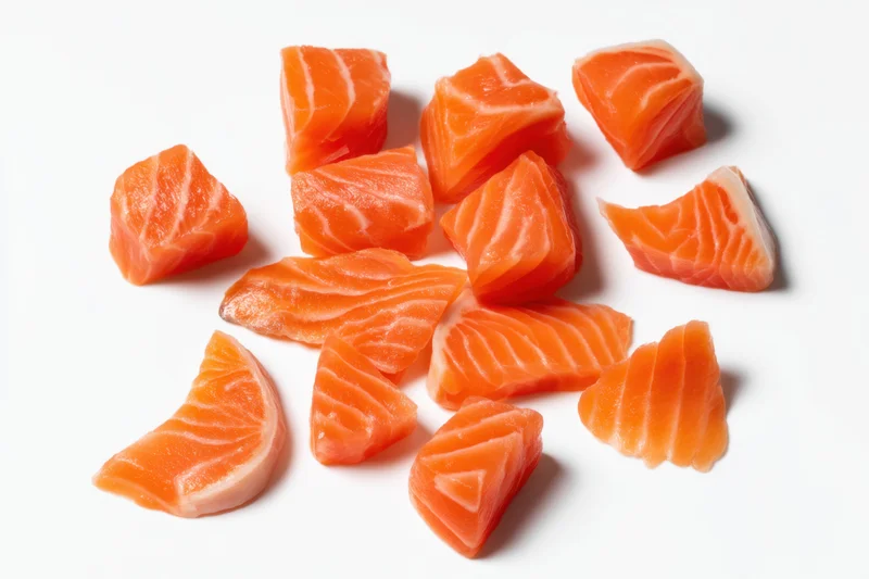 Raw salmon chunks arranged on a white background with copyspace