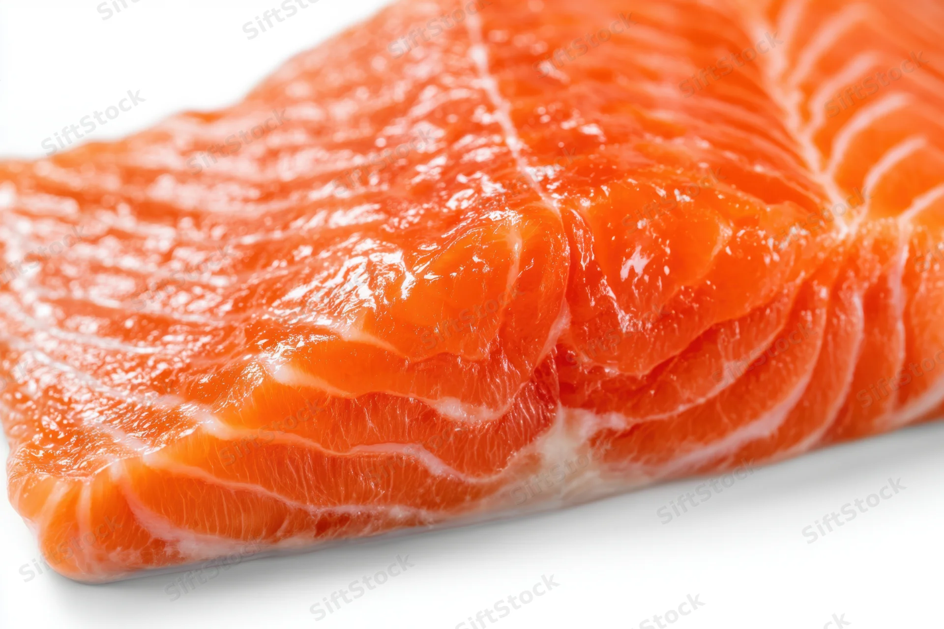 Raw salmon fillet with visible fat striations on white background