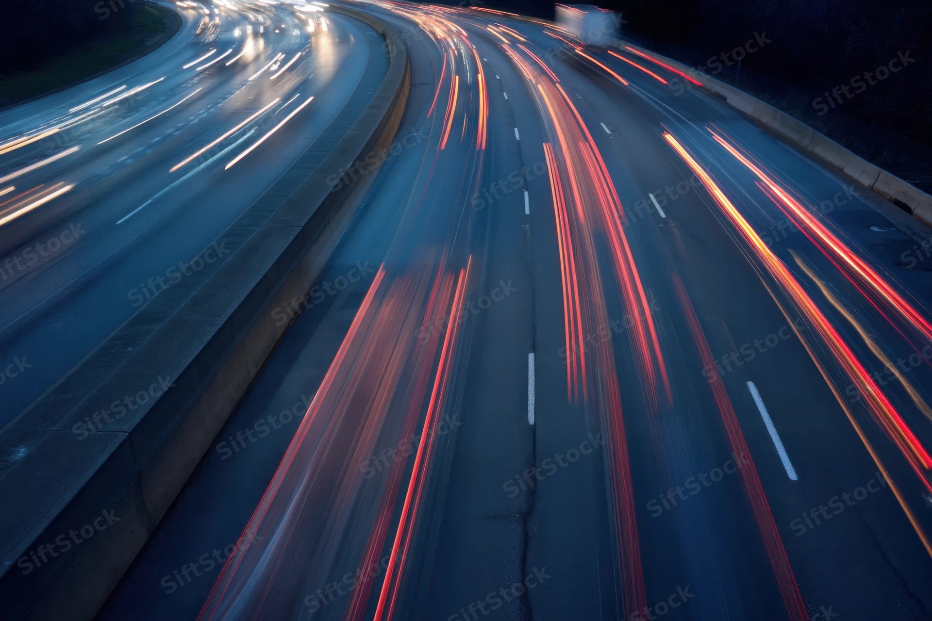 Highway traffic at dusk with vehicles creating light streaks from motion blur