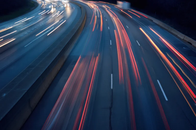 Highway traffic at dusk with vehicles creating light streaks from motion blur