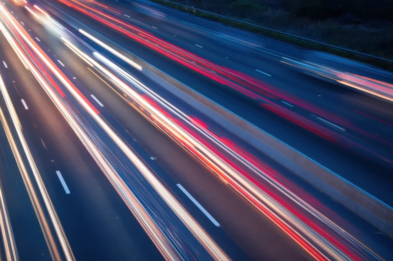Moving vehicles creating light streaks on a highway at dusk
