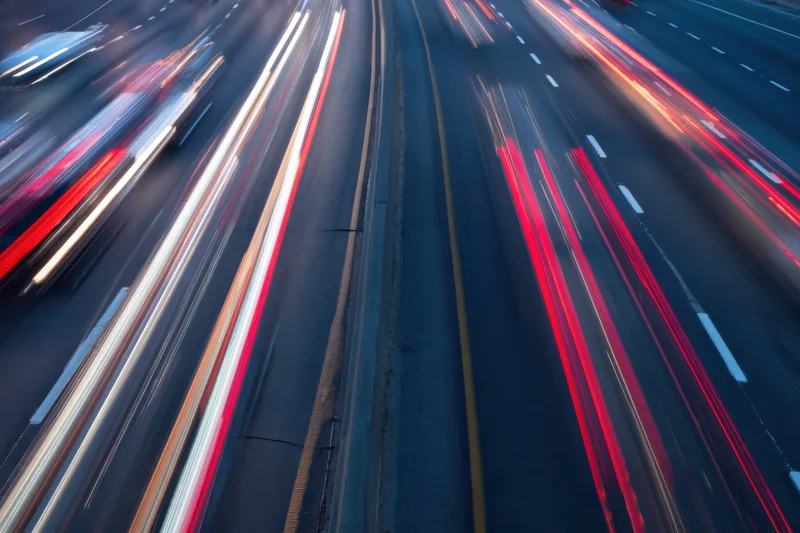 Moving vehicles creating light streaks on a highway at dusk