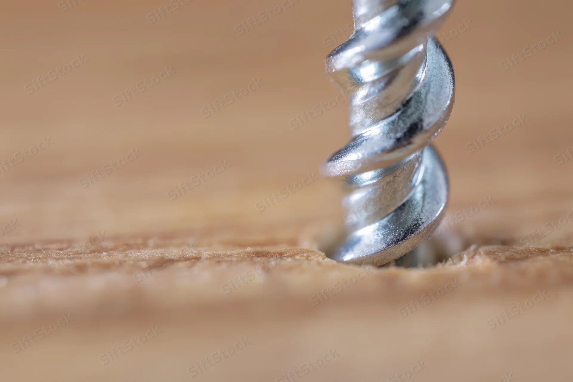 Metal screw embedded in wooden surface with visible grain and thread detail
