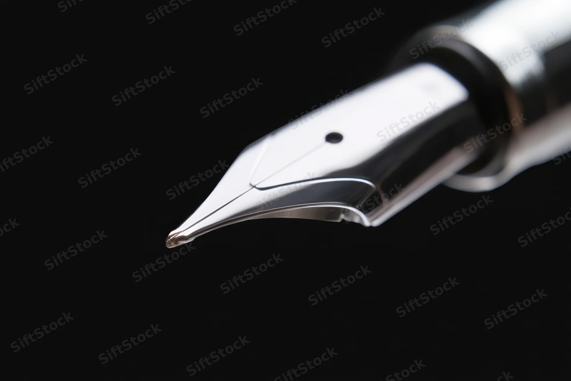 Close-up of a sleek metallic fountain pen nib against black background