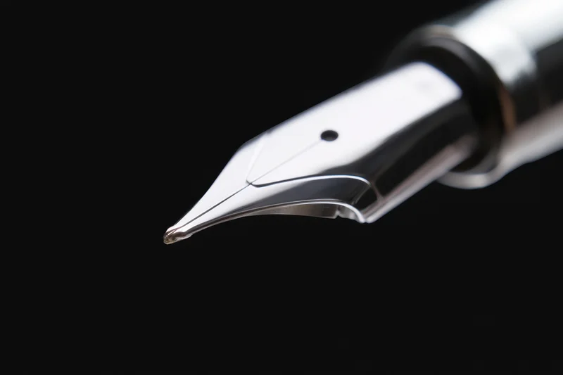 Close-up of a sleek metallic fountain pen nib against black background