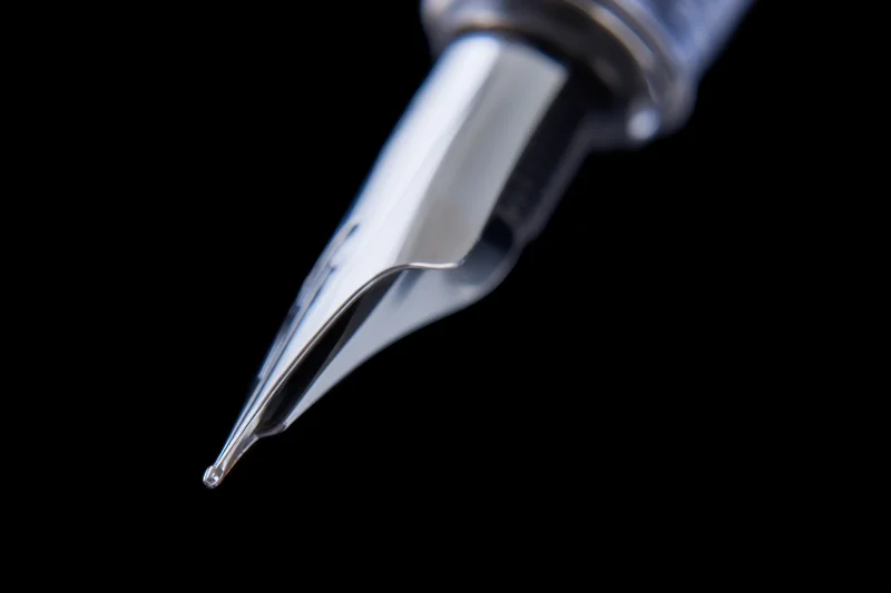 Close-up of a sleek metallic fountain pen nib against black background