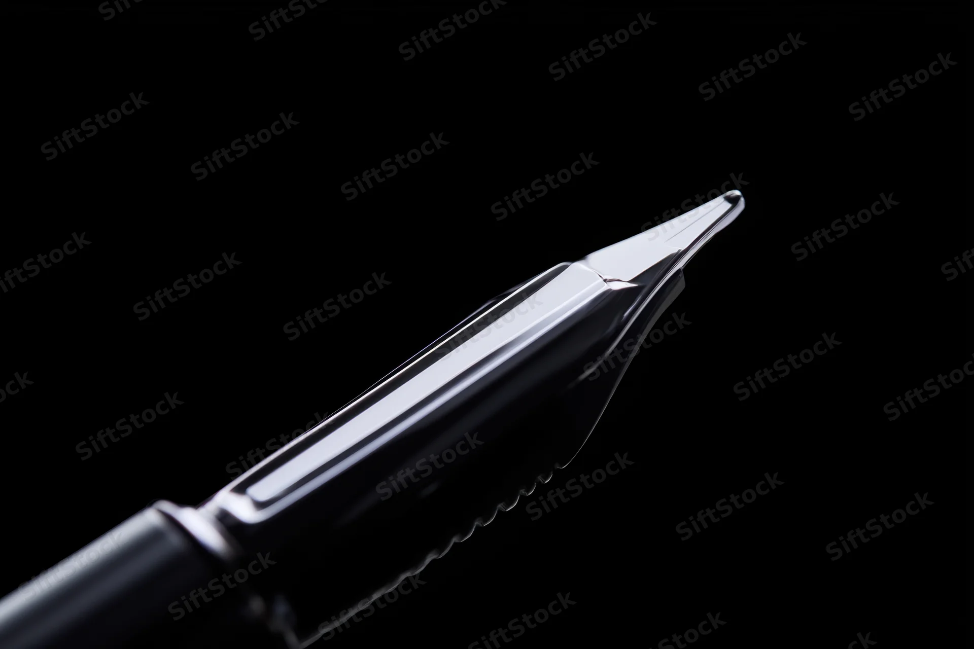 Close-up of a sleek metallic fountain pen nib against black background