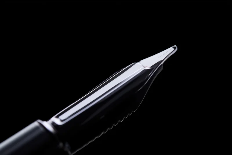 Close-up of a sleek metallic fountain pen nib against black background
