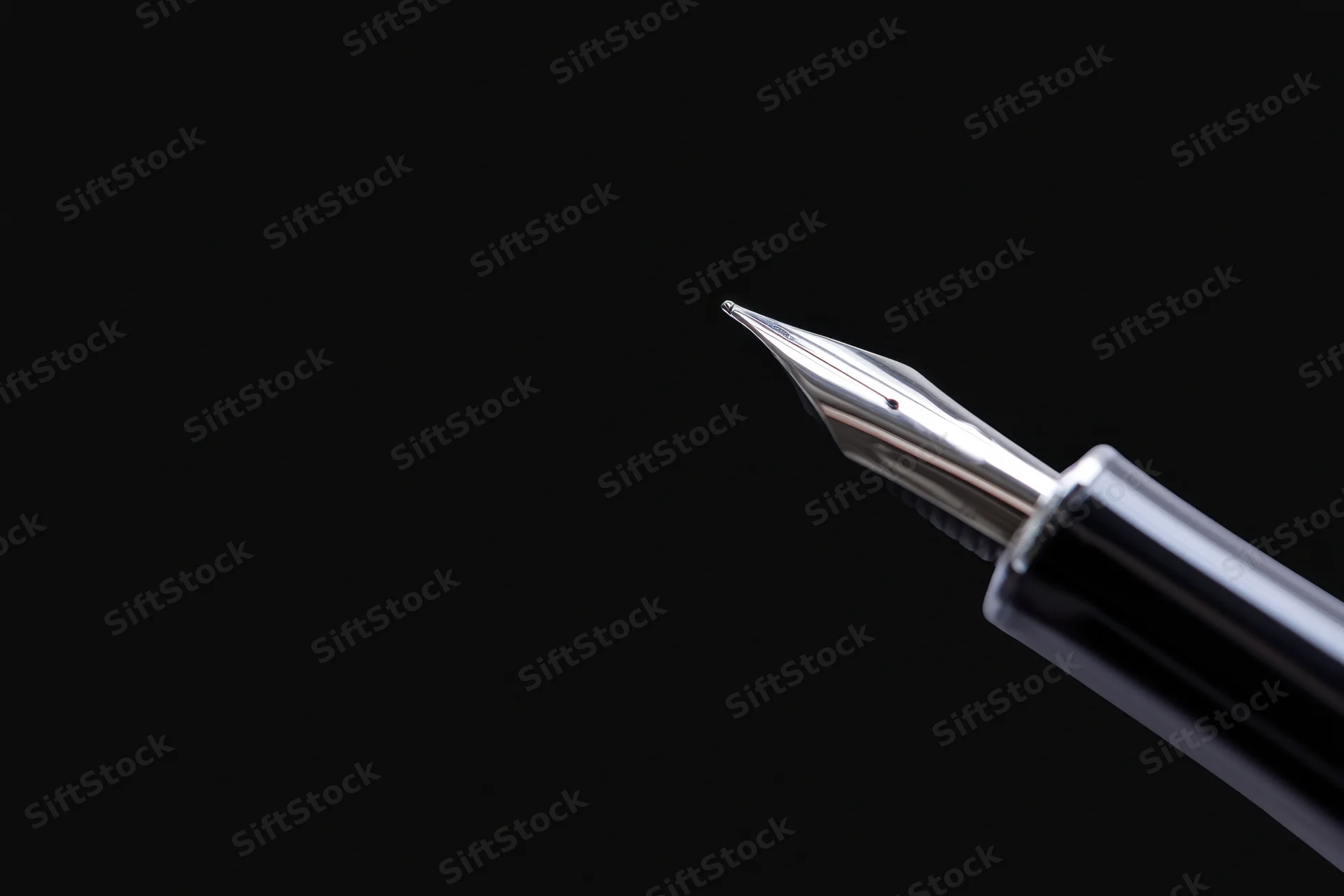 Close-up of a sleek metallic fountain pen nib against a black background