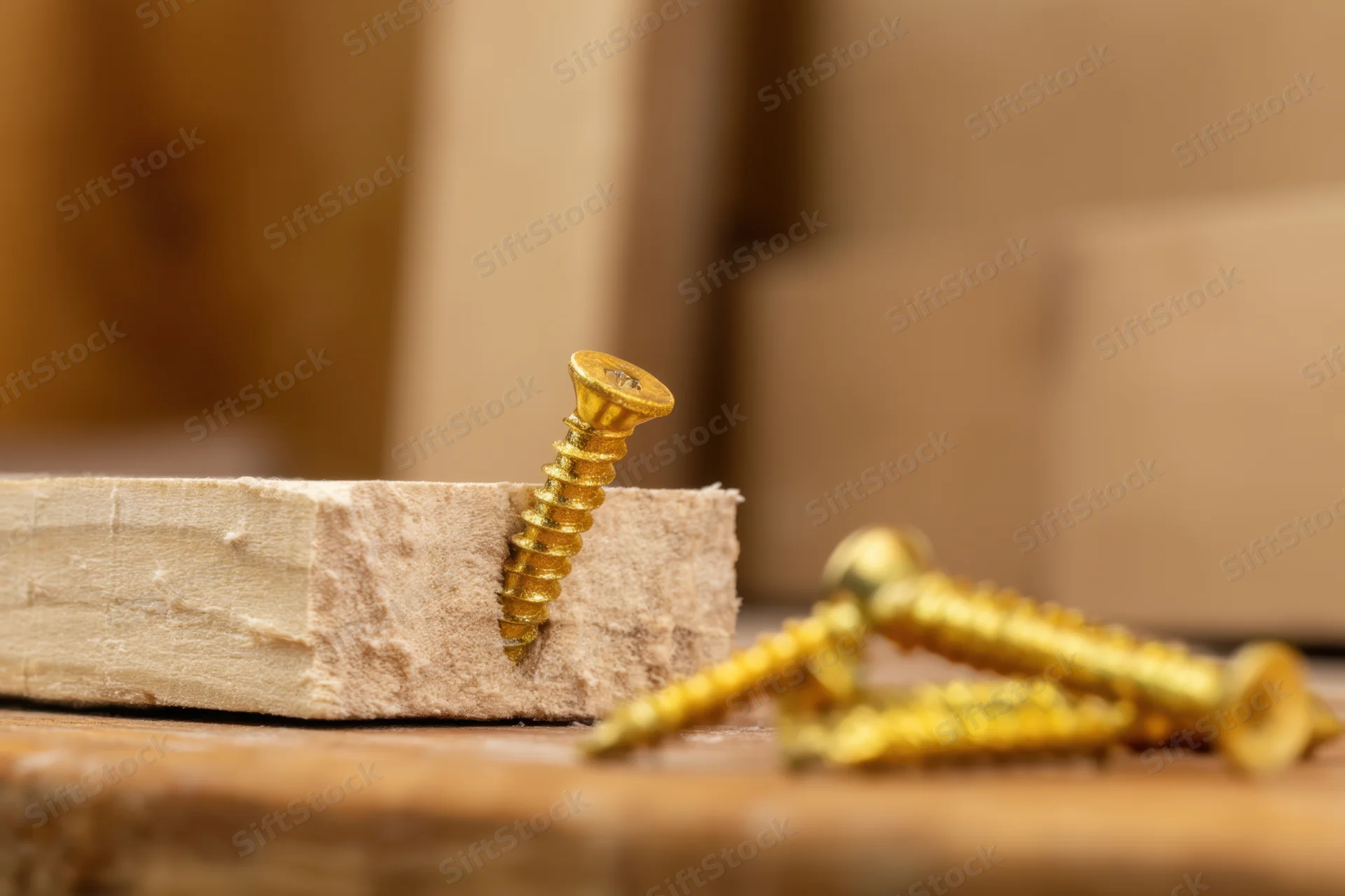 Golden screw embedded in a wooden plank with additional screws nearby on a workbench surface