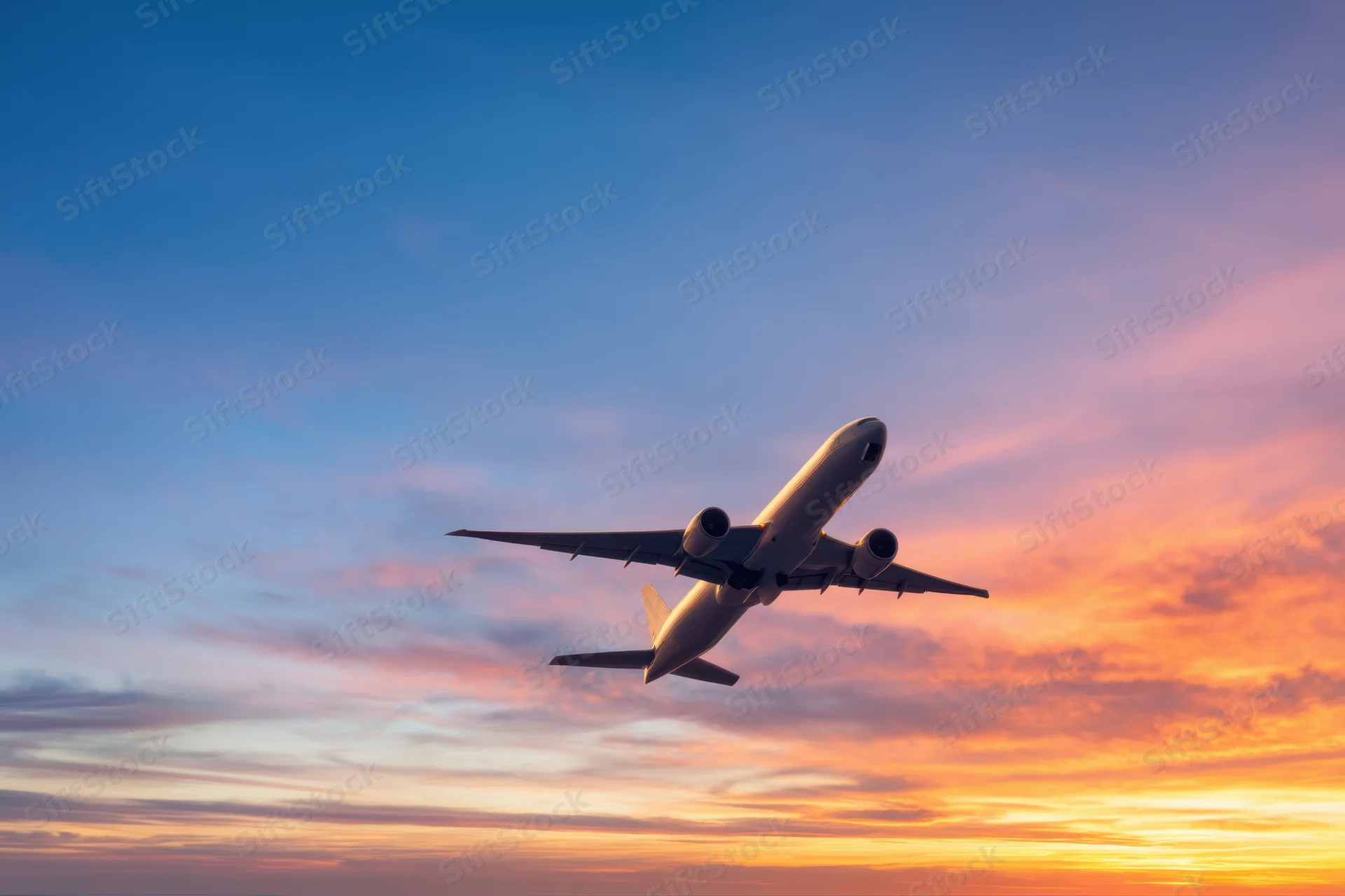 Commercial airplane ascending into twilight sky with colorful sunset horizon