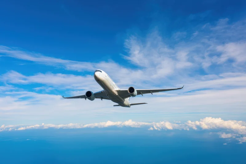 Commercial airplane in flight above clouds against blue sky