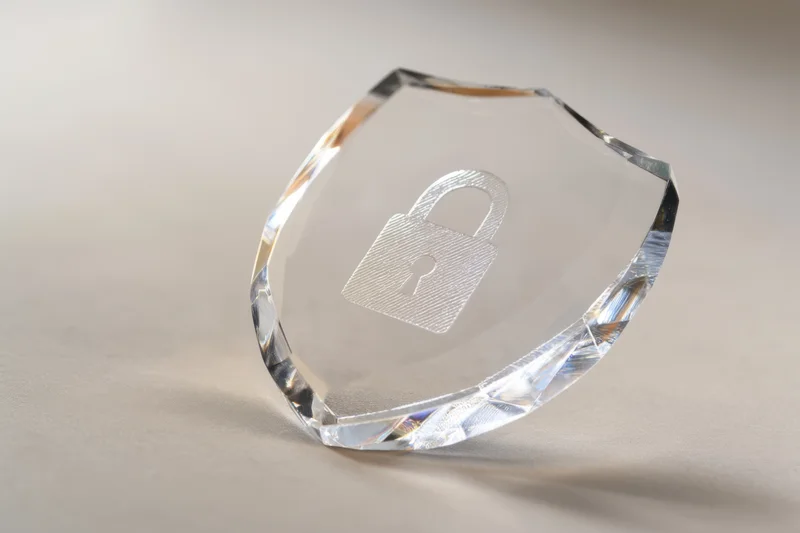 Crystal shield with engraved lock icon resting on a neutral surface