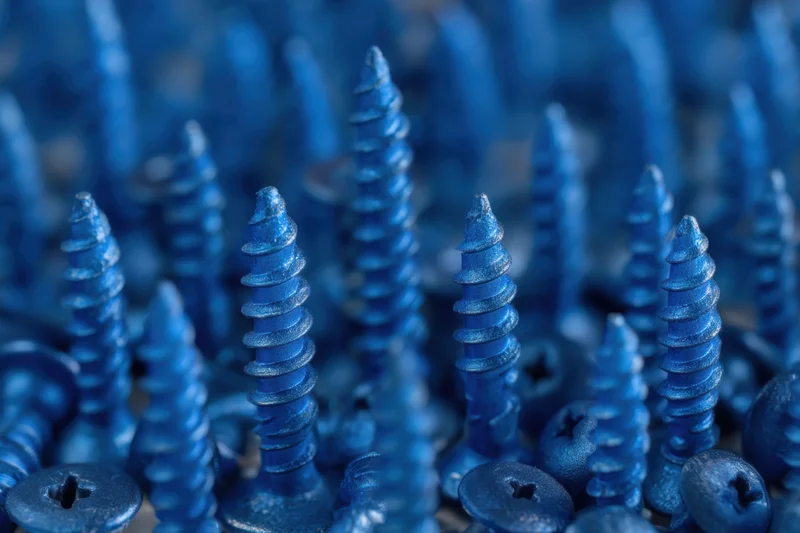 Dense arrangement of blue metallic screws with matte finish in close-up view