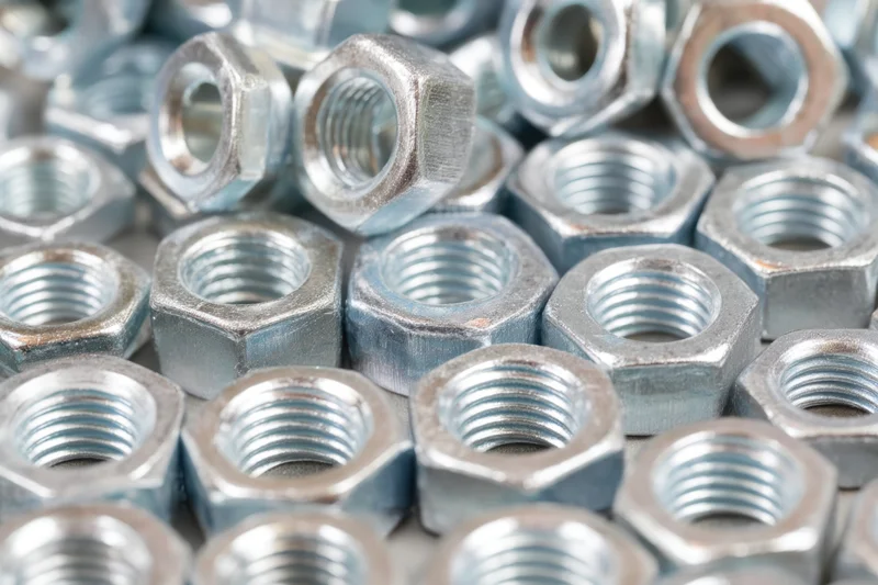 Closeup of metallic hex nuts and bolts densely arranged in a pile