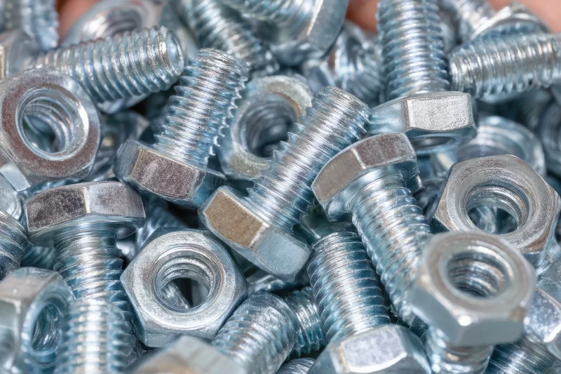 Dense pile of metallic bolts and nuts arranged closely together