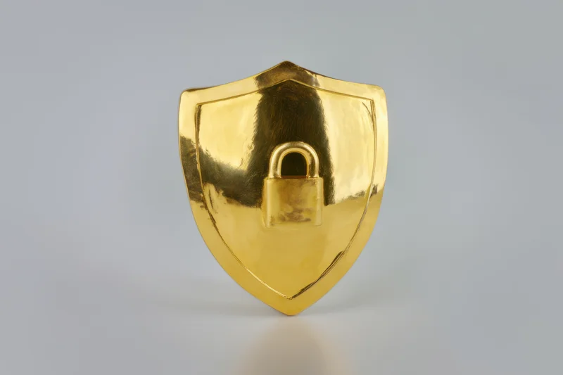 Golden shield with a padlock symbol centered on a plain surface