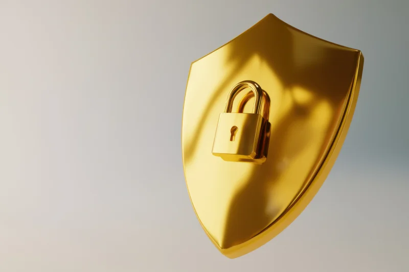 Golden shield with a padlock symbol centered on a plain background