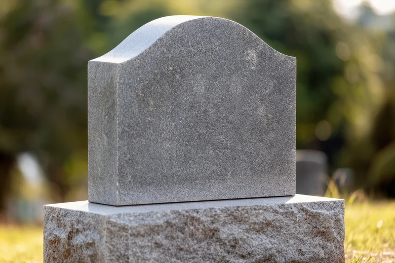 Granite tombstone with smooth polished surface standing on a stone base in a cemetery