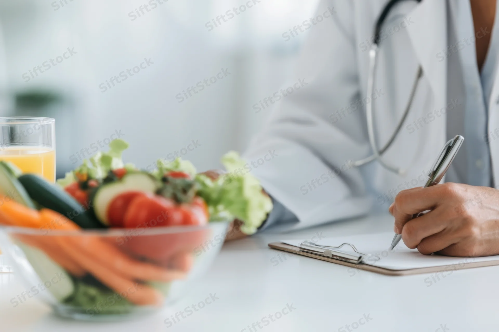 Doctor writing notes during nutrition consultation with vegetables on desk