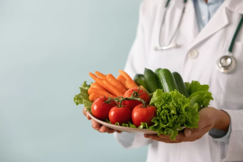 Doctor holding plate of fresh vegetables in a clinical setting