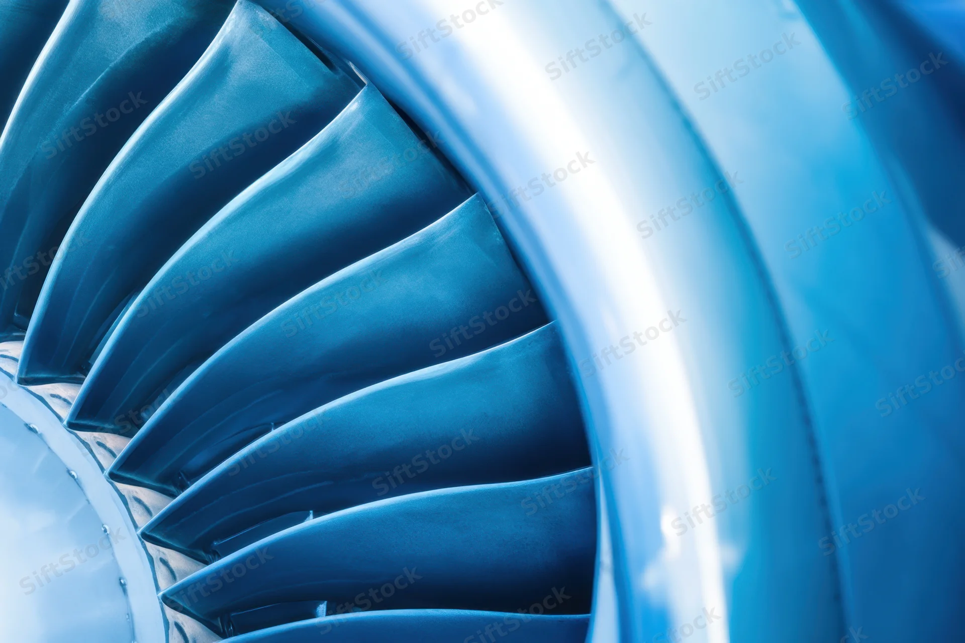 Closeup of jet engine turbine blades arranged in circular pattern showing metallic blue blades and smooth casing