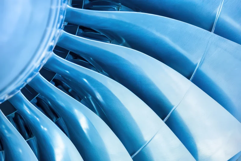 Close-up of jet engine turbine blades arranged in circular pattern showing metallic surface and curved structure