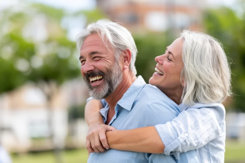 Senior couple laughing and hugging outdoors in a park setting
